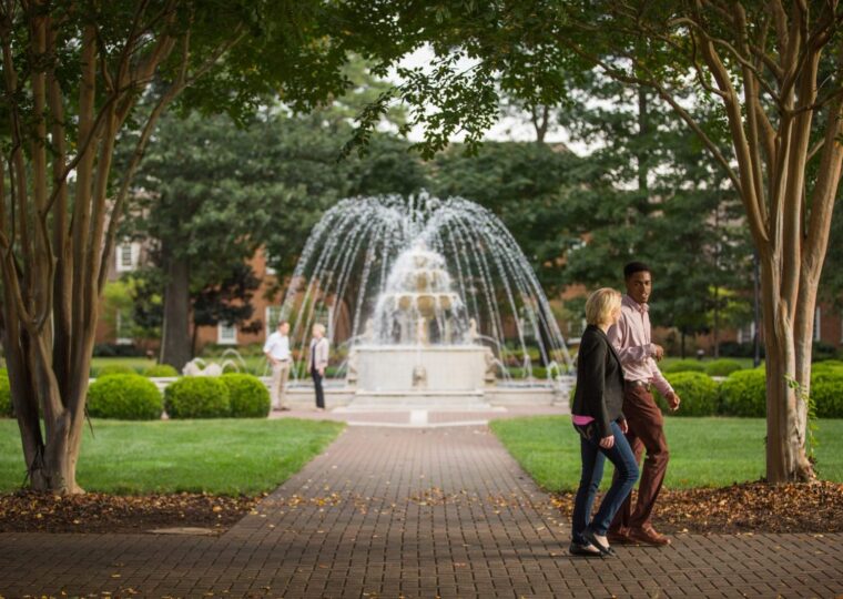 A student studying beside the campus fountain